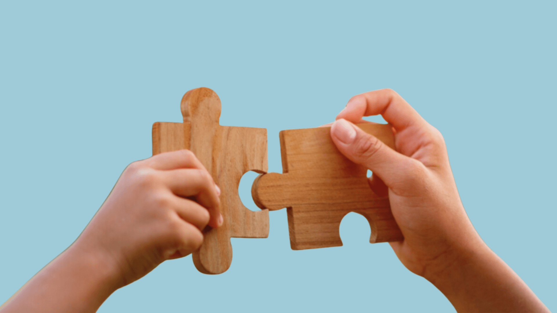 To hender holder trepuslespillbrikker mot en ensfarget, lyseblå bakgrunn, mens de fører brikkene sammen slik at de passer.
